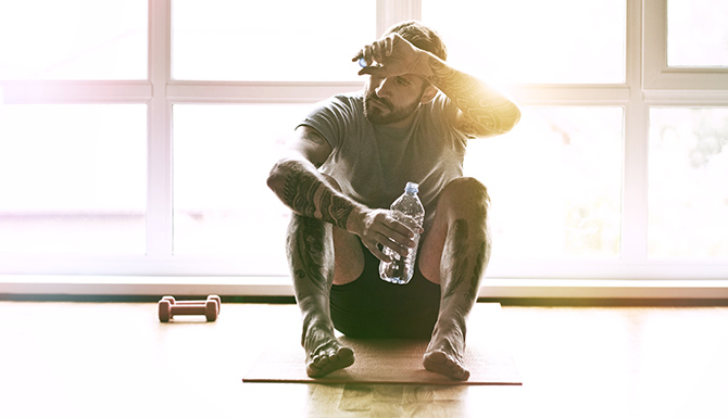 Hombre bebiendo agua con los ojos cerrados luego de ejercicios